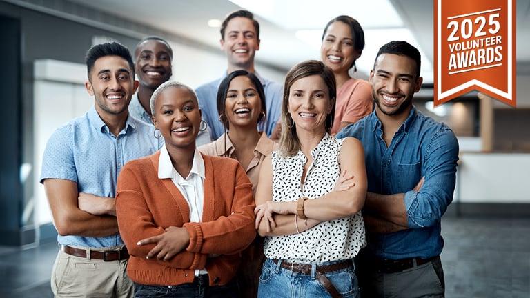 A group of smiling professionals in business casual stand for the camera